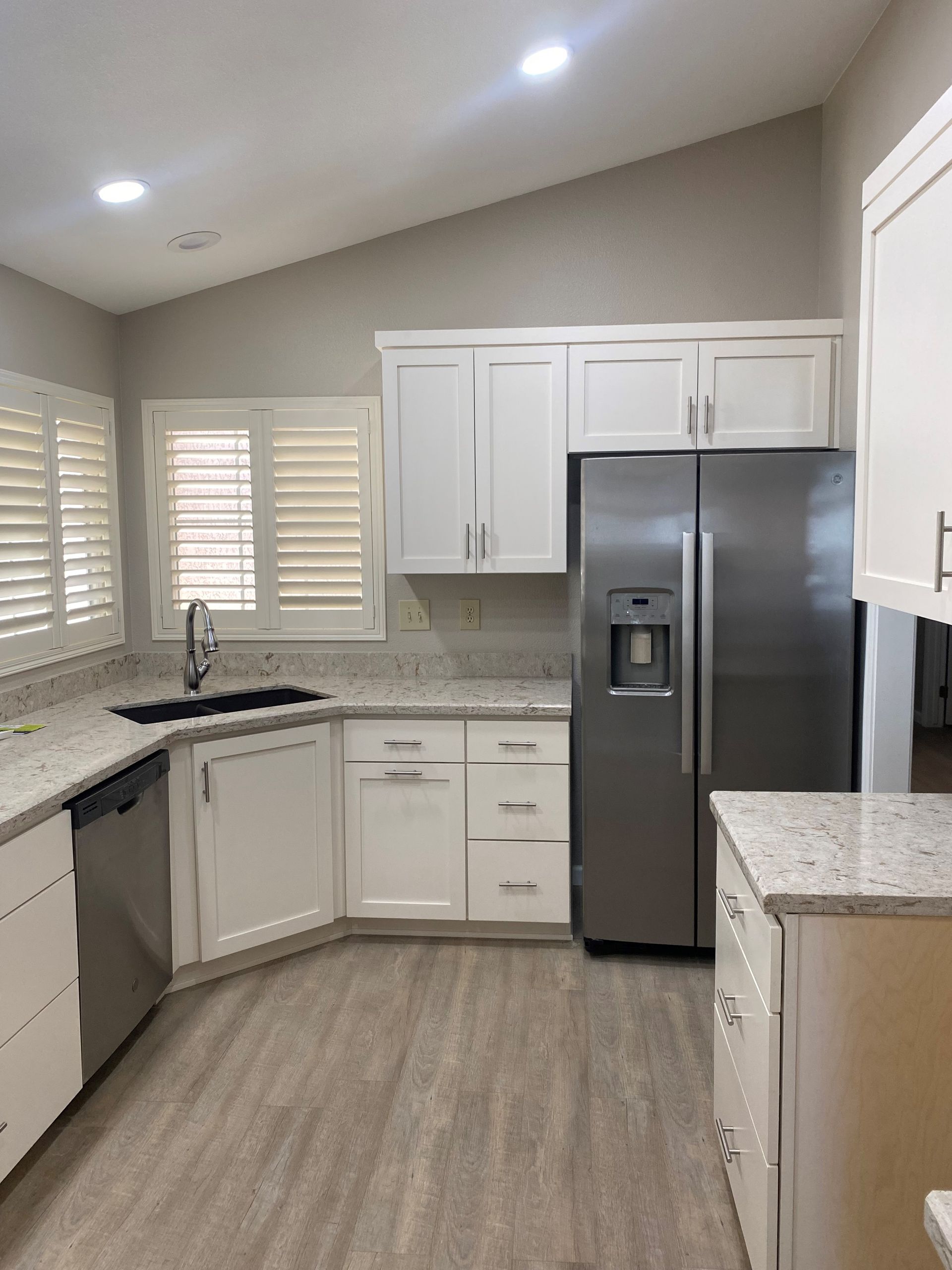 A kitchen with white cabinets and a stainless steel refrigerator