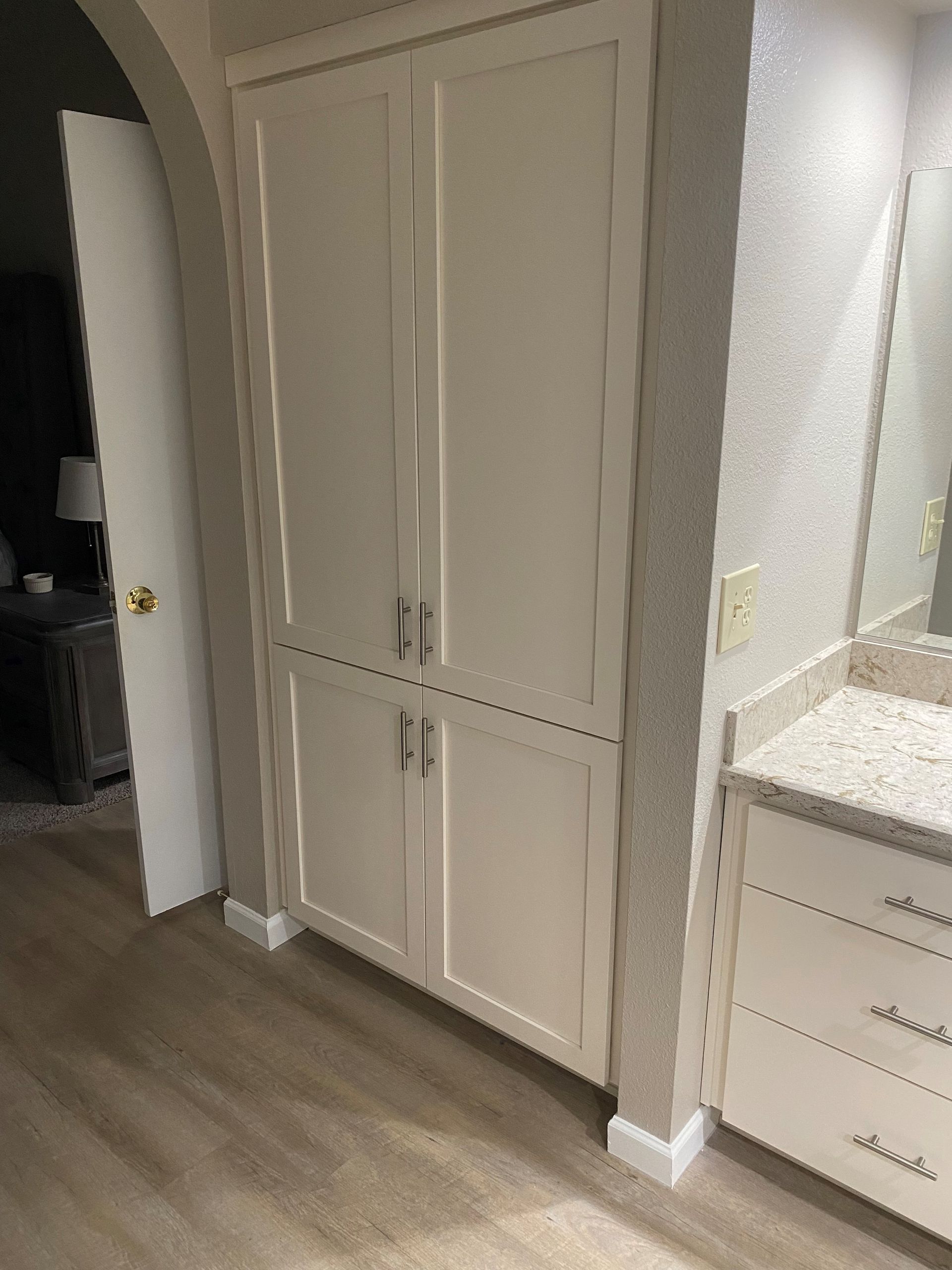 A bathroom with white cabinets , a sink and a mirror.