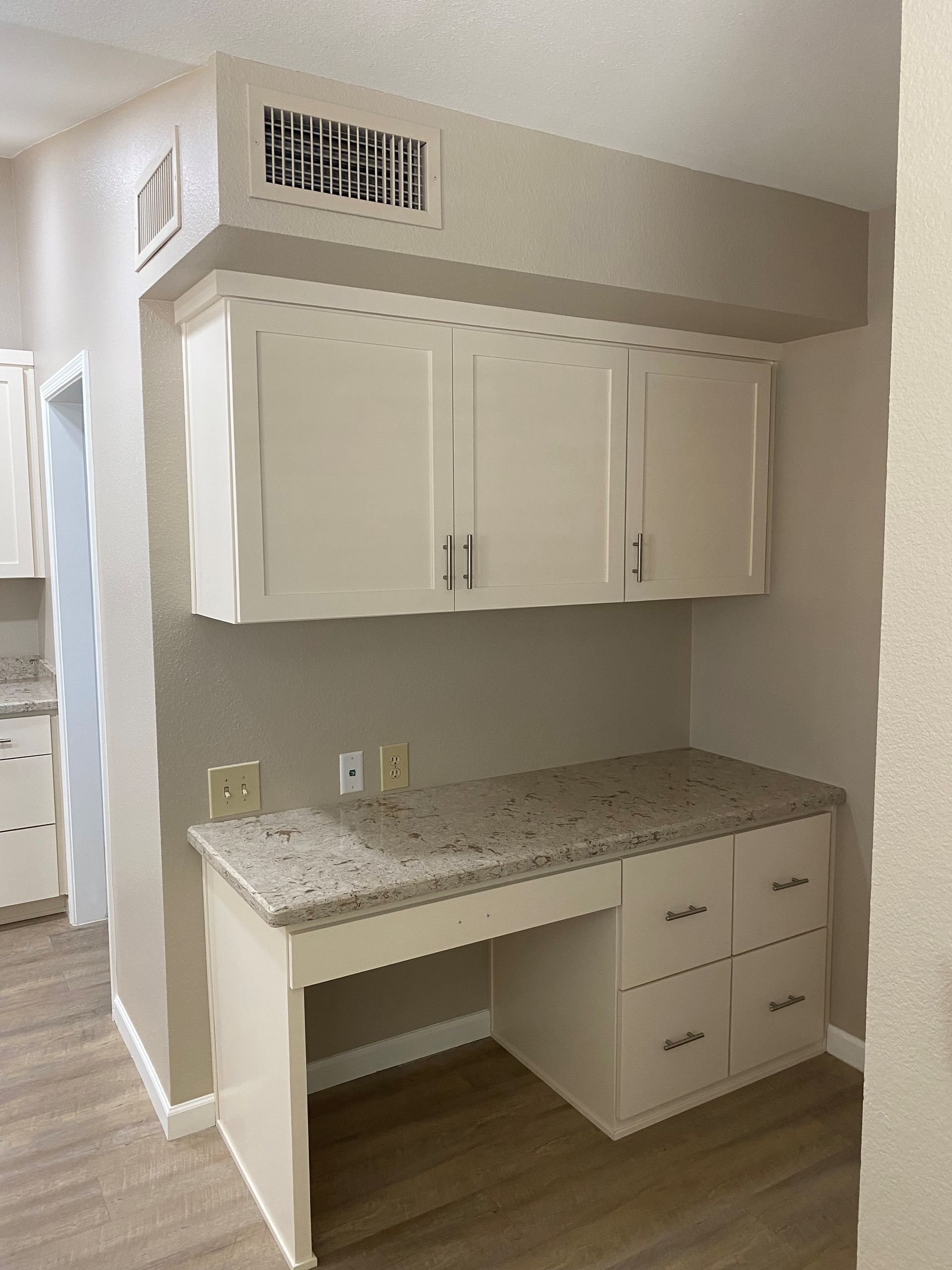 A kitchen with white cabinets and a granite counter top.