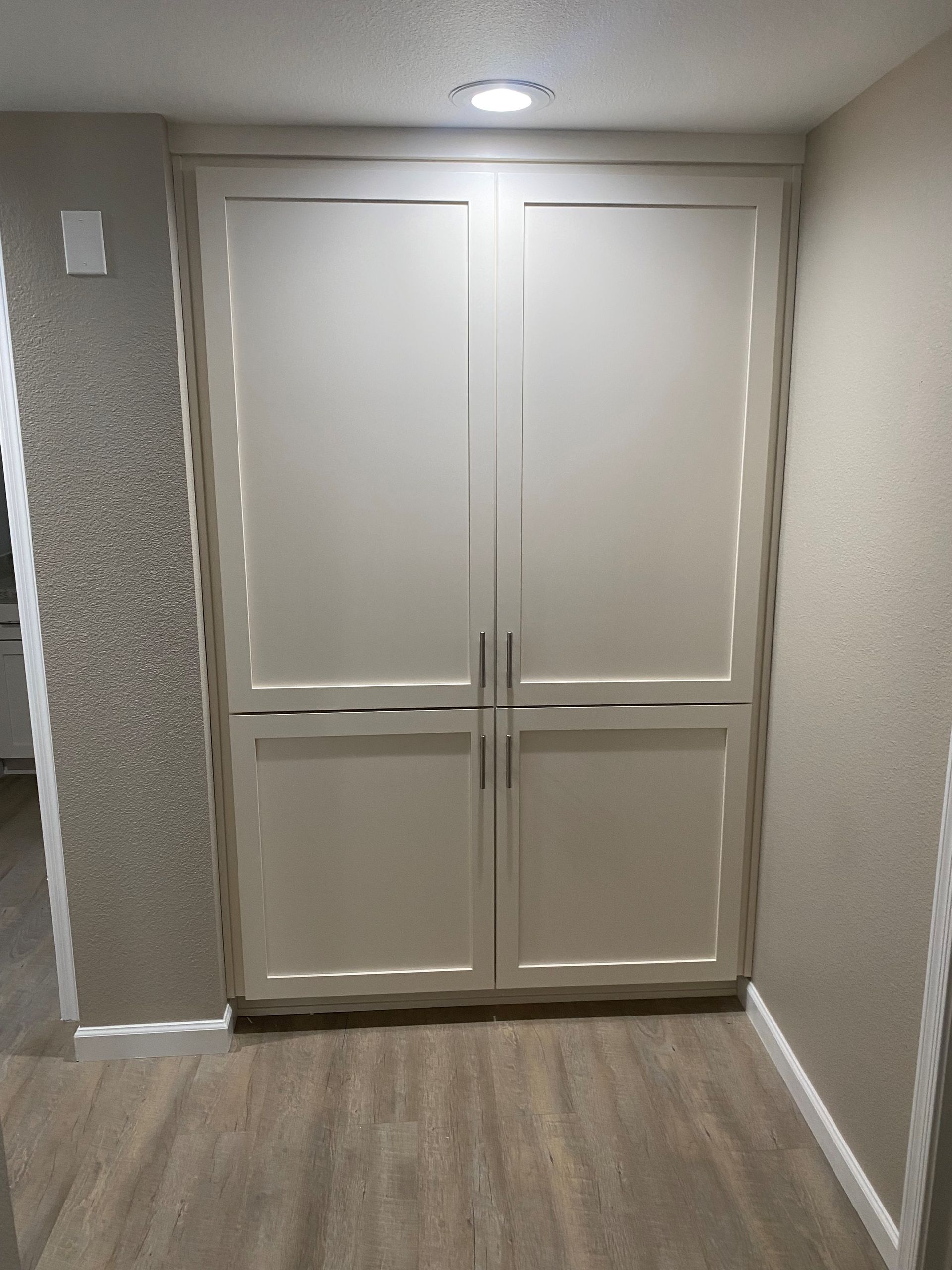 A hallway with white cabinets and a light on the ceiling