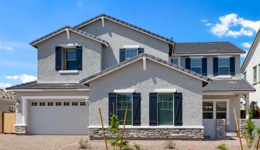 Two-story stucco house, gray with dark blue shutters. Sunny day with blue sky.