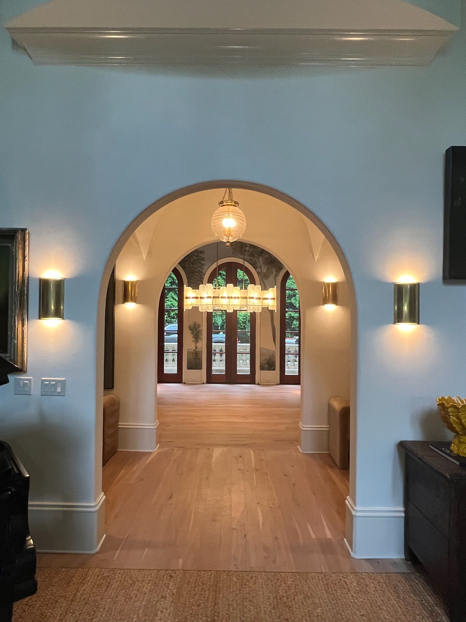 Arched hallway with blue walls, wood floors, and stained-glass doors at the far end.
