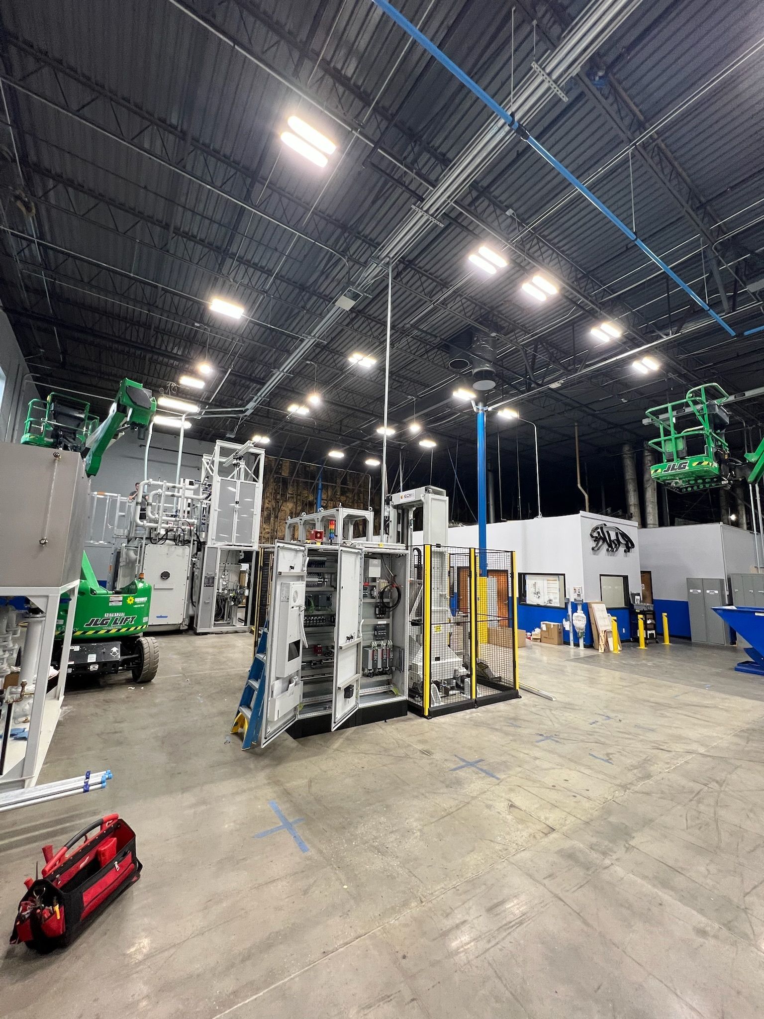 Large industrial warehouse with machinery, overhead lights, and a red toy truck on the floor