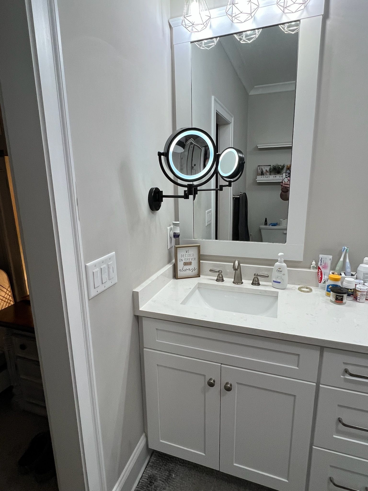 Bathroom vanity with white countertop, mirror, and chrome sink fixtures beside a wall outlet.