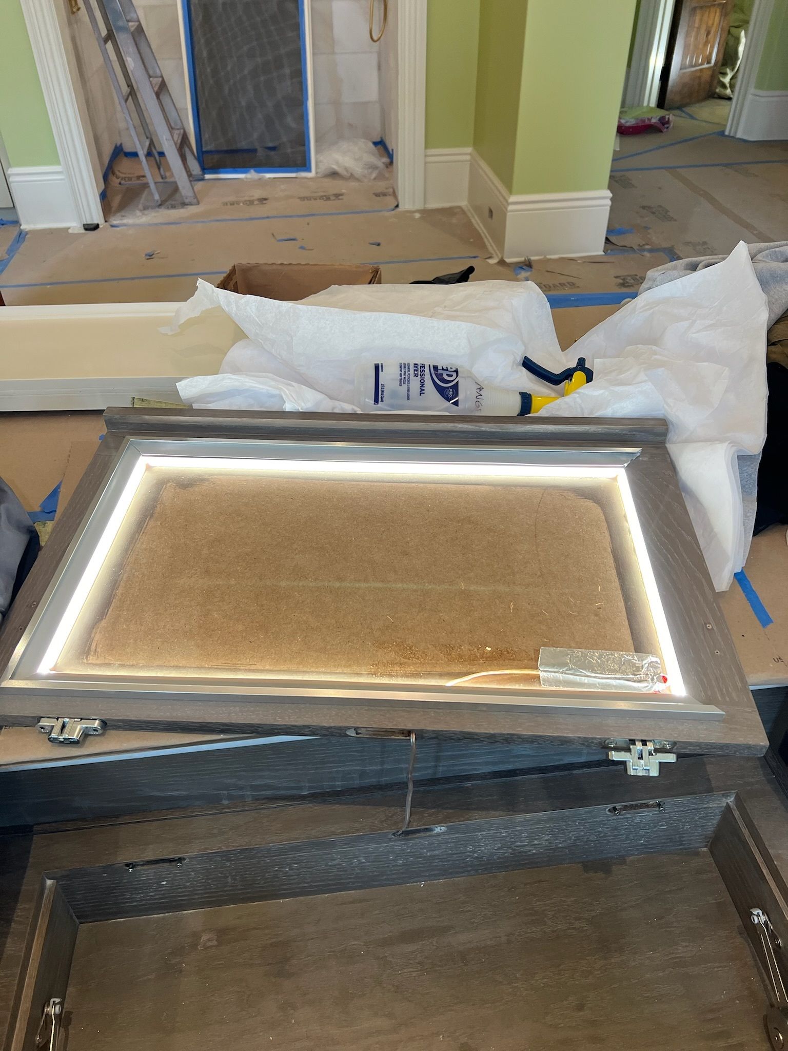 Framed door panel wrapped in plastic on a workbench inside a renovated room.