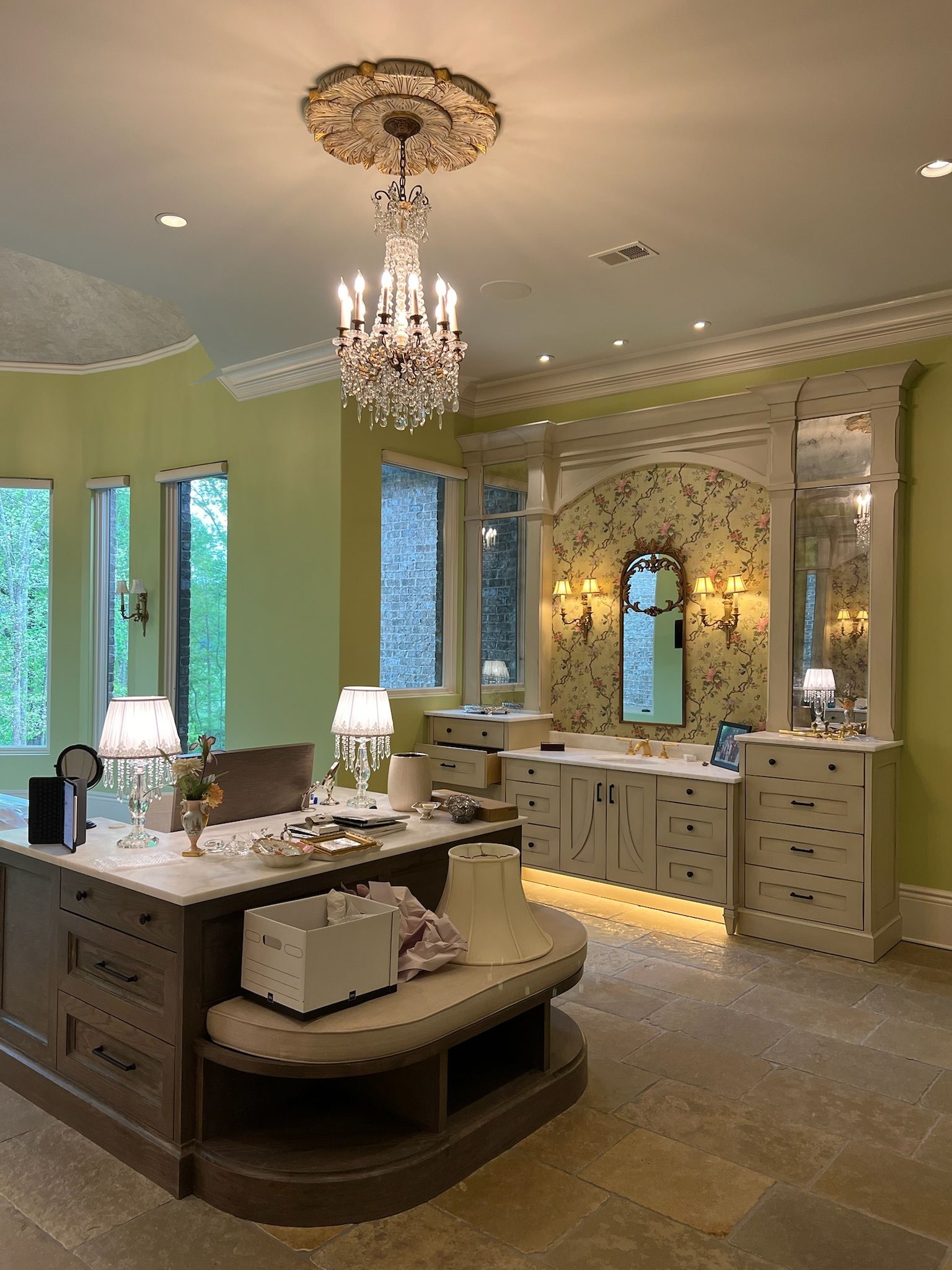 Elegant bathroom vanity with chandelier, mirrored cabinets, and double sinks in a pale green interior