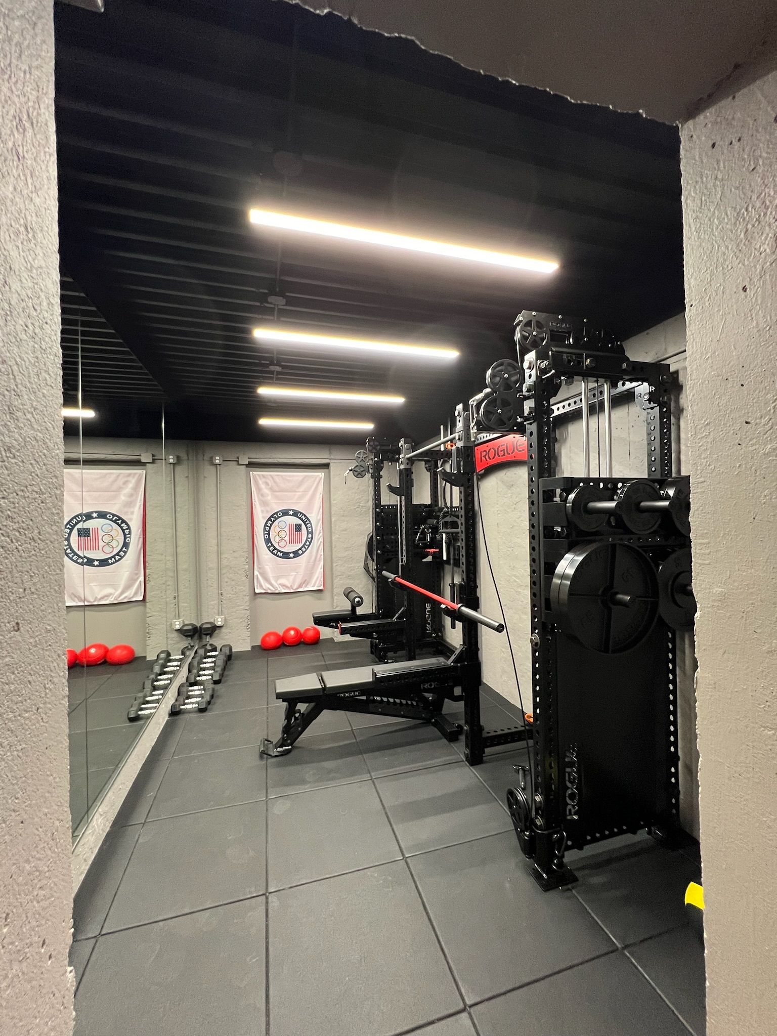 Modern gym interior with weight bench, dumbbells, cable machine, and padded flooring
