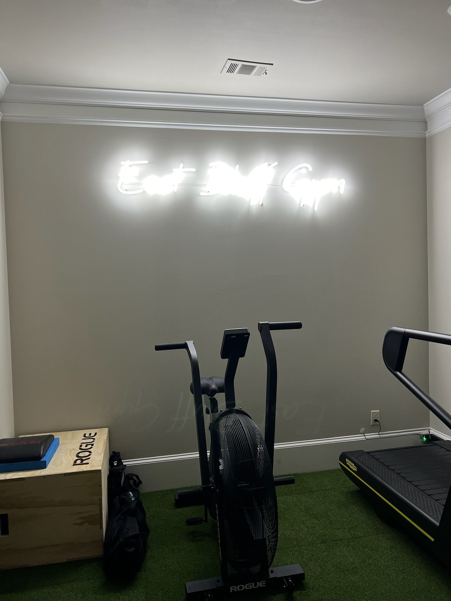 Indoor gym with an elliptical, treadmill, and wall mirror on a gray wall