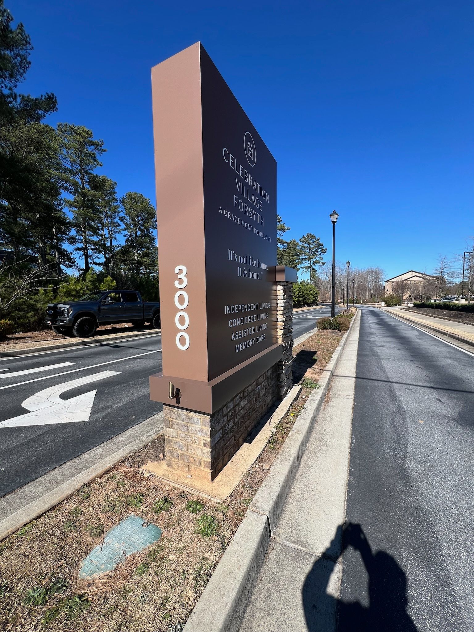 Tall brown roadside sign marked “3000” beside a paved road on a sunny day