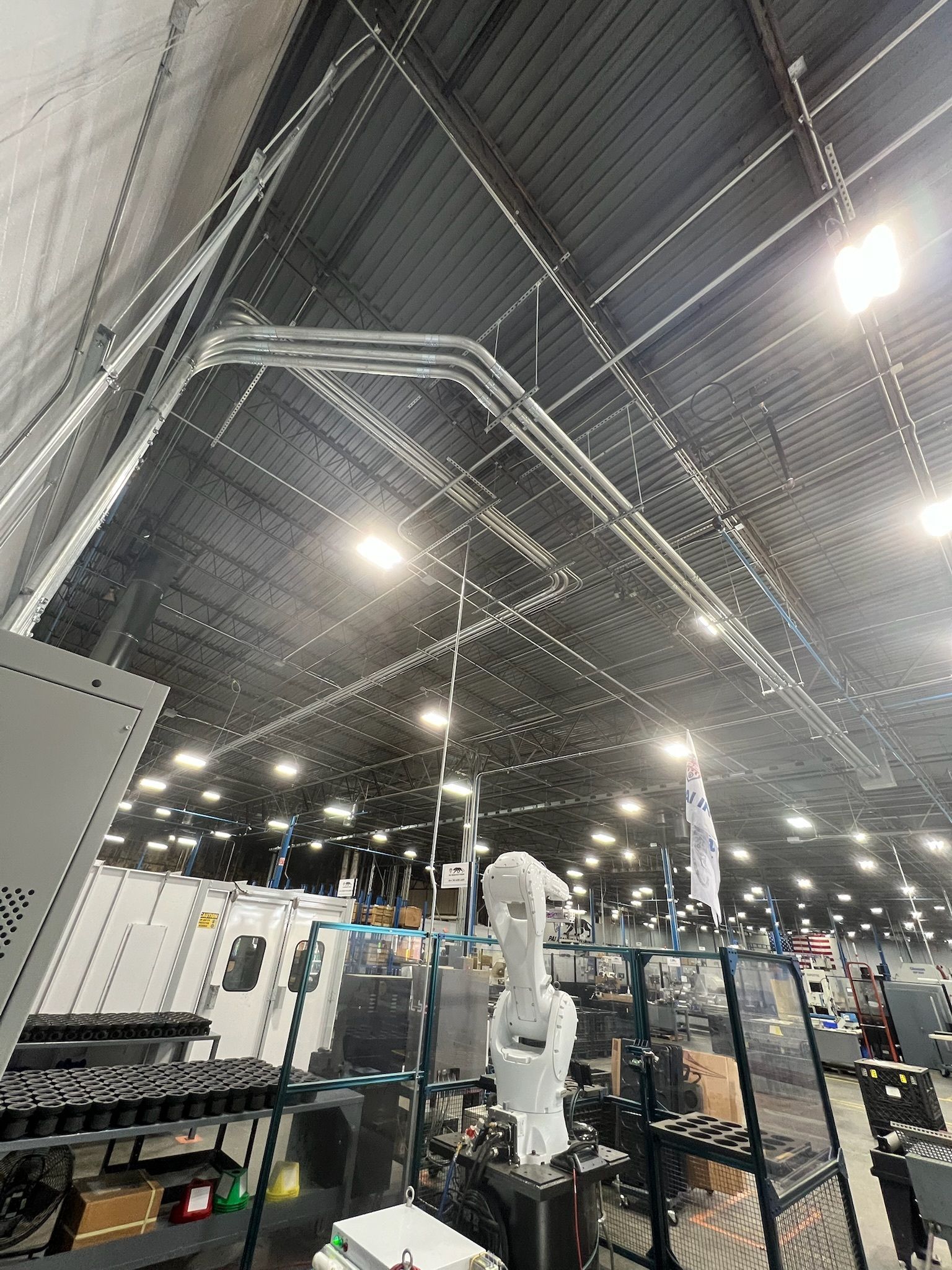 Industrial exhibition hall with a white robotic arm on display under bright overhead lights