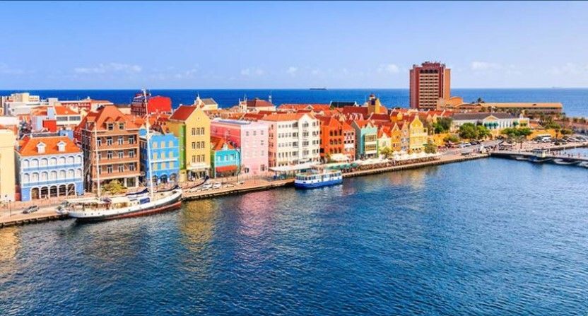 Colorful waterfront buildings along a harbor with blue water and a clear sky