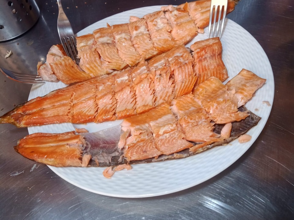 Warm gerookte forel wordt op een wit bord in stukken verdeeld