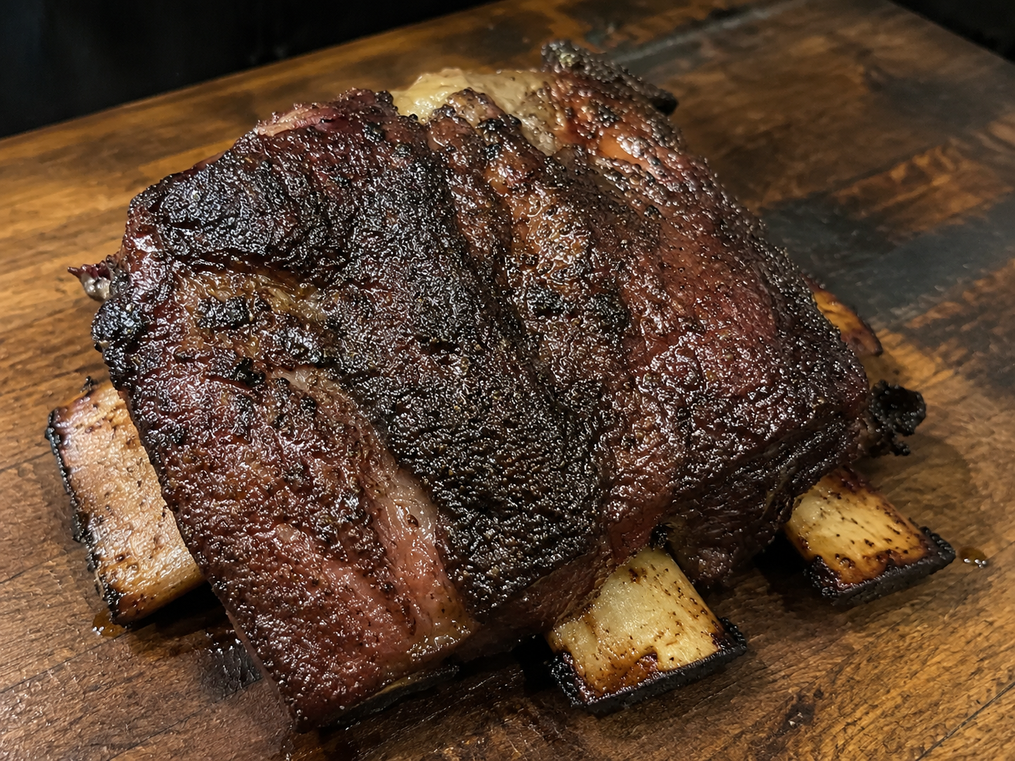 Runder short ribs met donkere bark en zichtbare ribben, langzaam gegaard op de BBQ