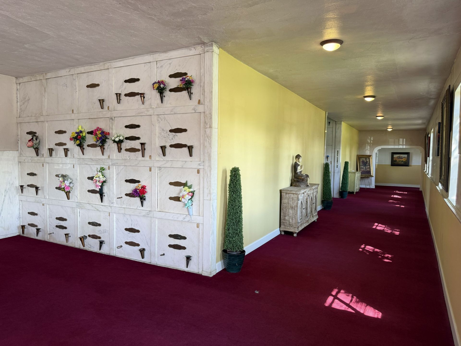 Interior hallway with a maroon carpet, white walls, and decorative wall niches