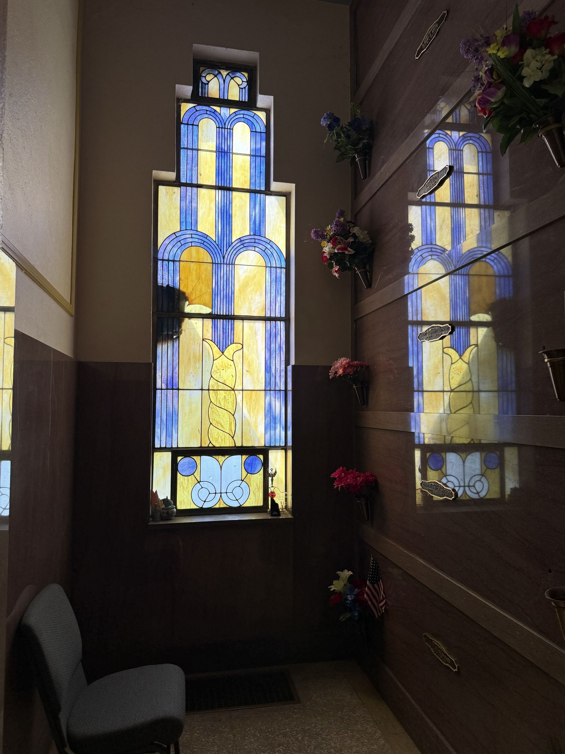 Stained-glass window glowing with blue and yellow patterns in a dim hallway.