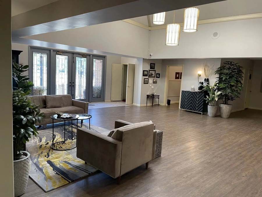 Spacious modern lobby with sofas, coffee table, plants, and glass doors leading outside.