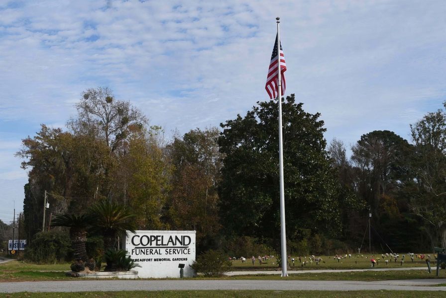 Copeland Park sign beside a tall flagpole with an American flag under a cloudy sky