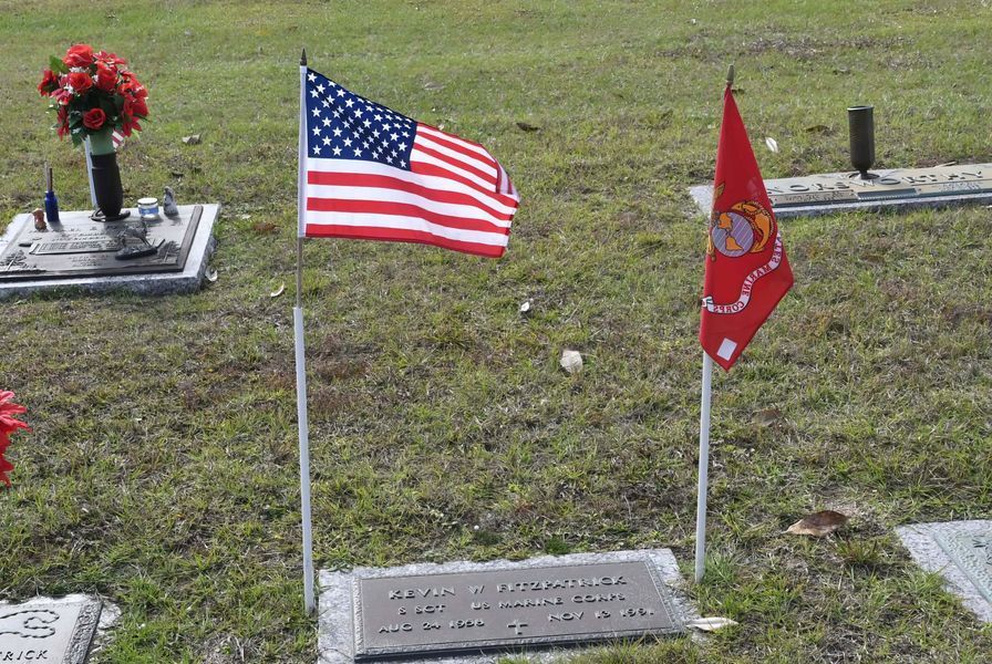 Grave marker with American and red military flags in a cemetery