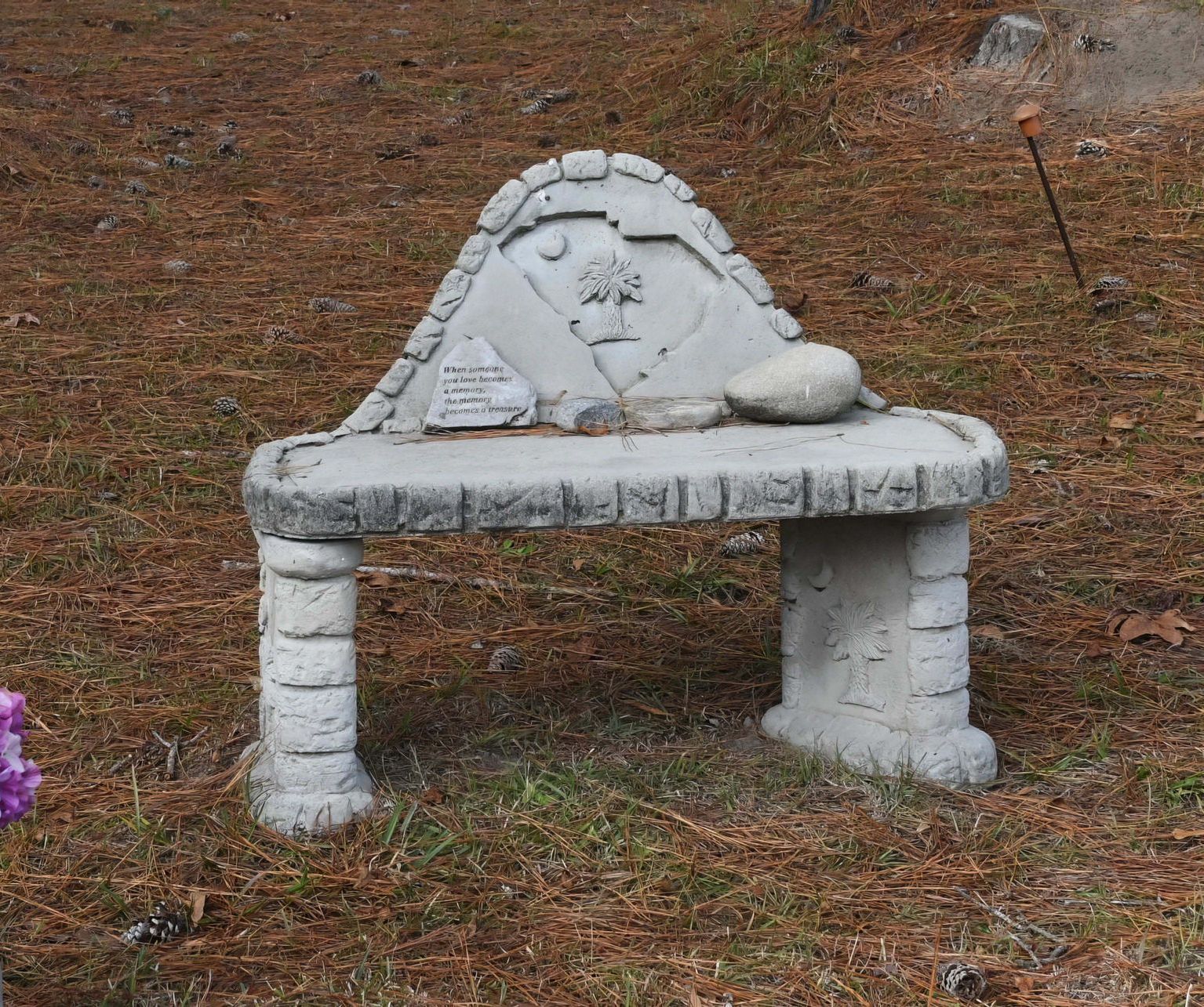 White stone garden bench with a decorative backrest on brown ground outdoors
