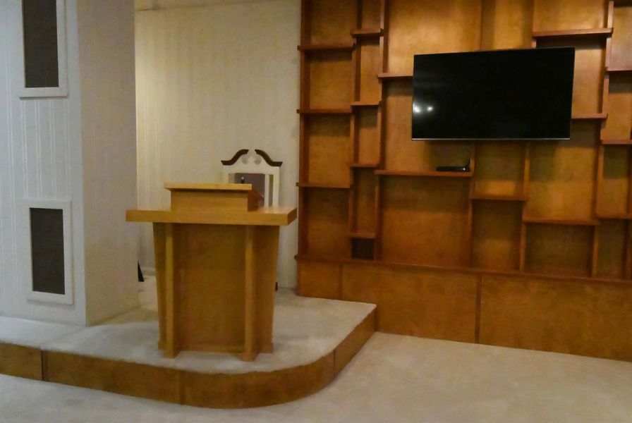 Podium in a wood-paneled room with a wall-mounted TV screen.