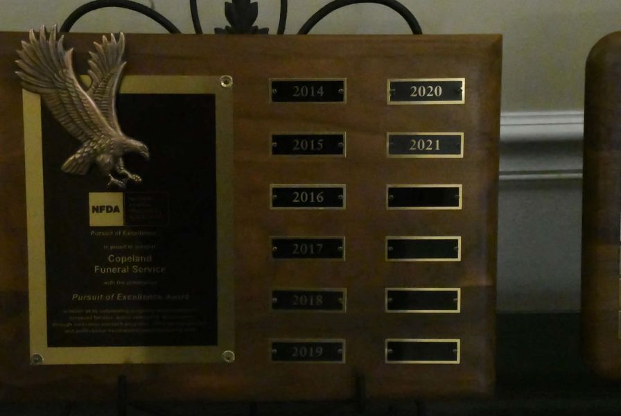Wooden awards plaque with eagle emblem and several engraved year plates on a table