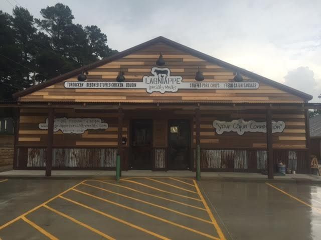 Log cabin-style storefront with a central entrance and yellow parking lines on a wet lot