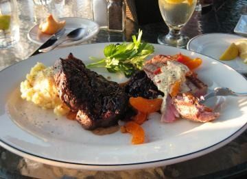 Plated grilled meat with mashed potatoes and vegetables on a table outdoors
