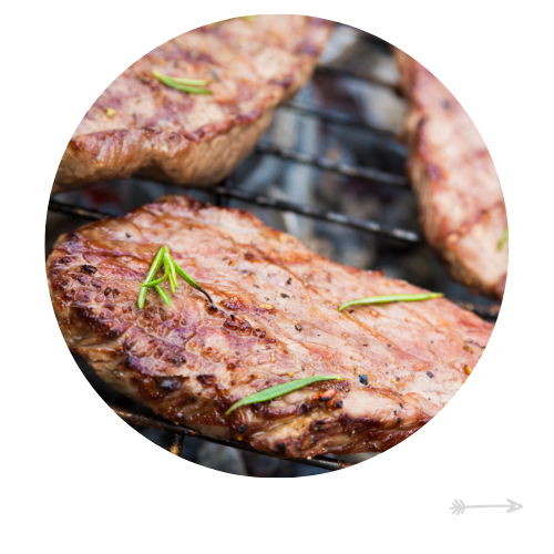 Steak grilling on a barbecue, topped with rosemary sprigs.