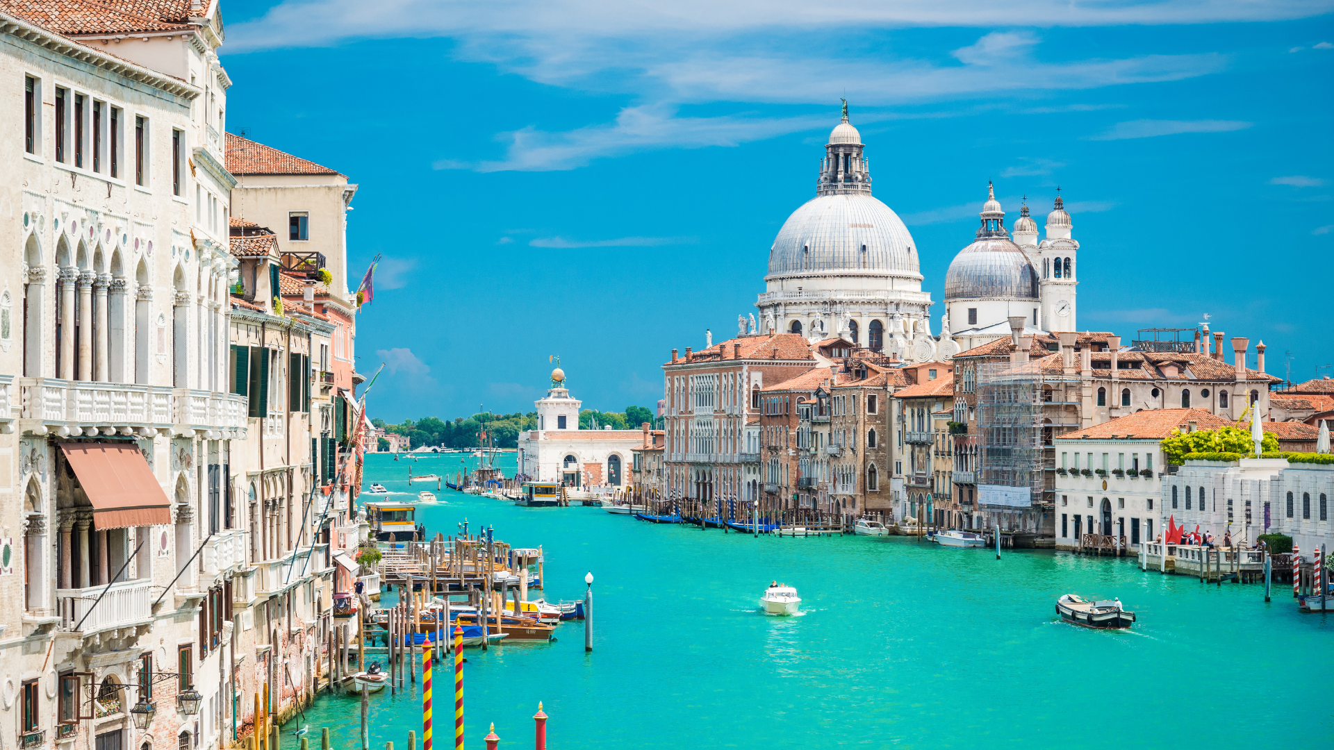 Venice canal with gondolas and the Basilica di Santa Maria della Salute under a bright blue sky