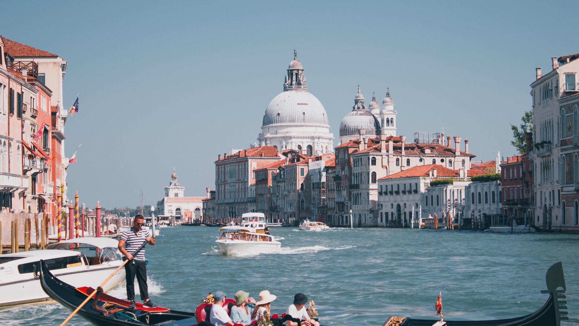 Gondola on Venice canal with Basilica di Santa Maria della Salute in the background under a clear blue sky