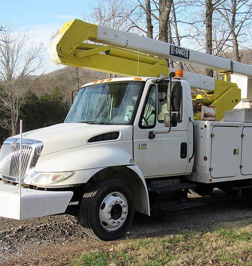 White utility truck with a yellow boom lift, parked outdoors.