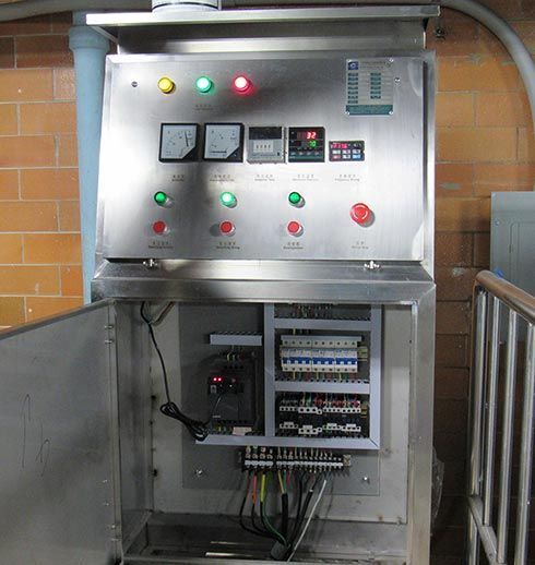 Stainless steel electrical control panel with gauges, lights, and open door revealing wiring.