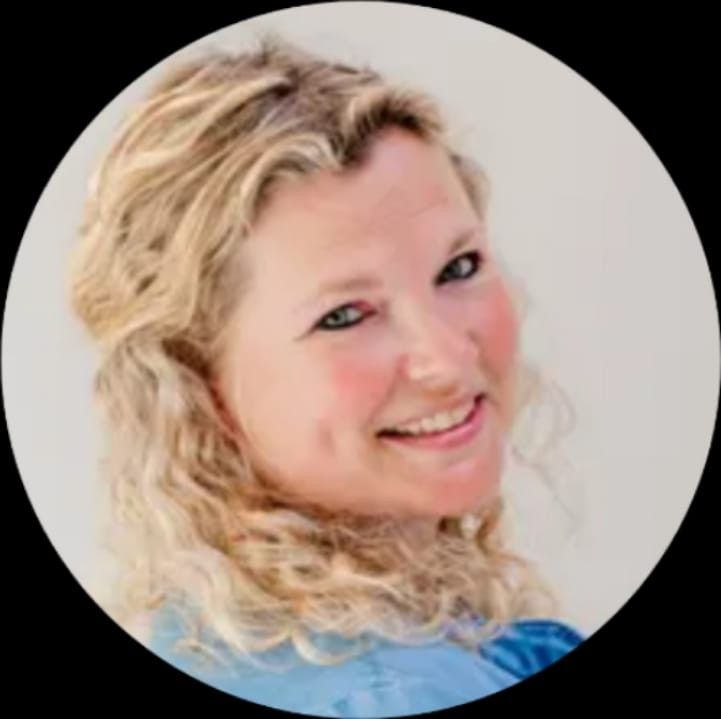 Een blonde vrouw met krullend haar glimlacht en kijkt over haar schouder.