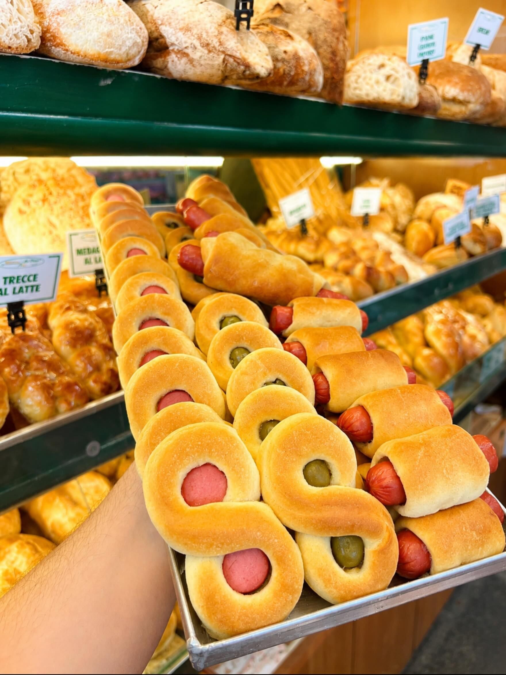 Vassoio di pasticcini colorati a forma di ciambella in una vetrina da pasticceria.