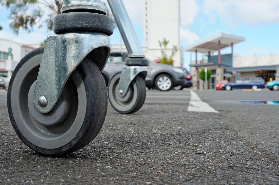 Un primer plano de la rueda de un carrito de compras en un estacionamiento.