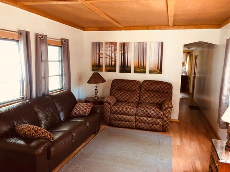 A living room with a couch , chair , lamp and paintings on the wall.
