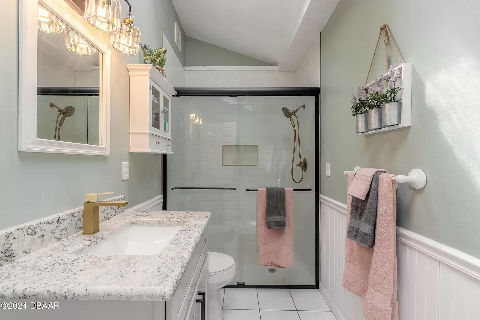 A bathroom with a sink , toilet , mirror and shower.