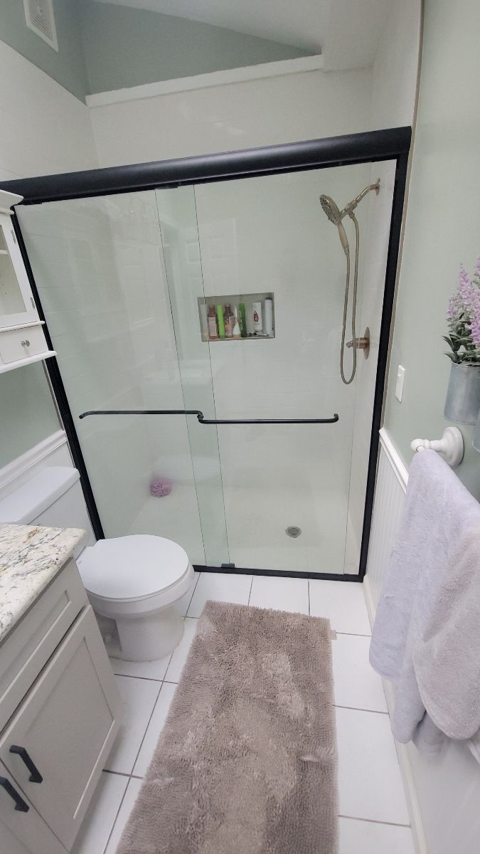 A bathroom with a toilet , sink and shower with a sliding glass door.