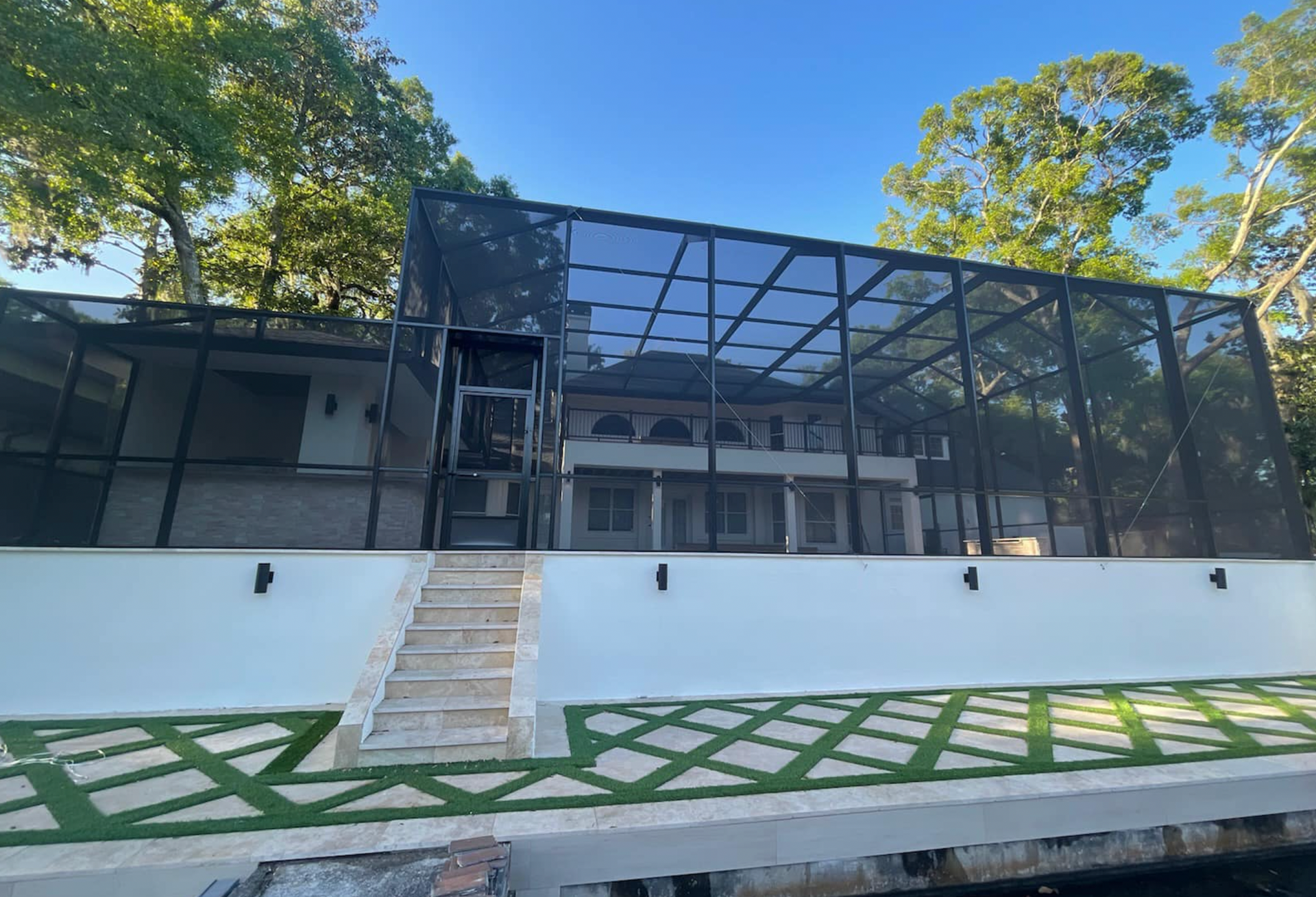 A large house with a screened in porch and stairs leading up to it.