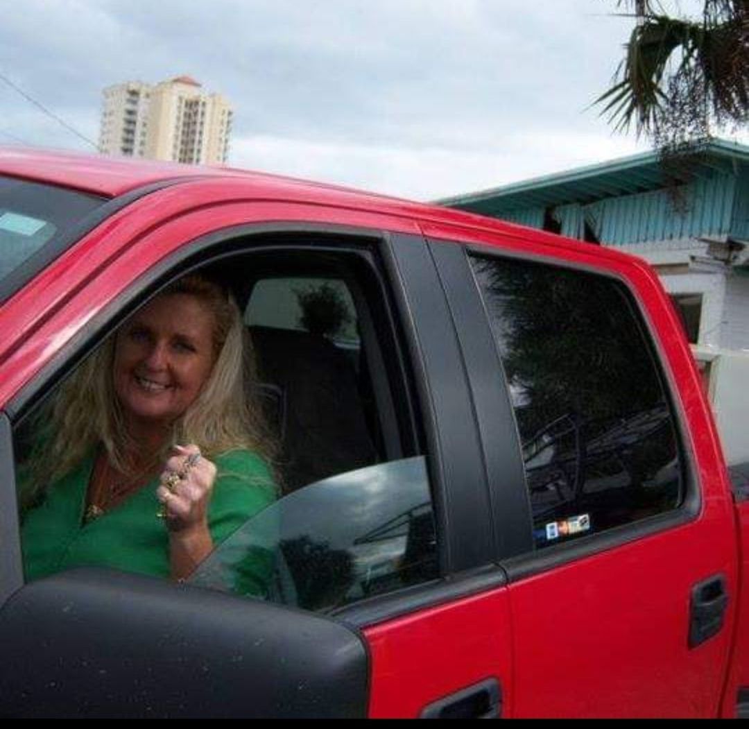 A woman in a green shirt is sitting in a red truck