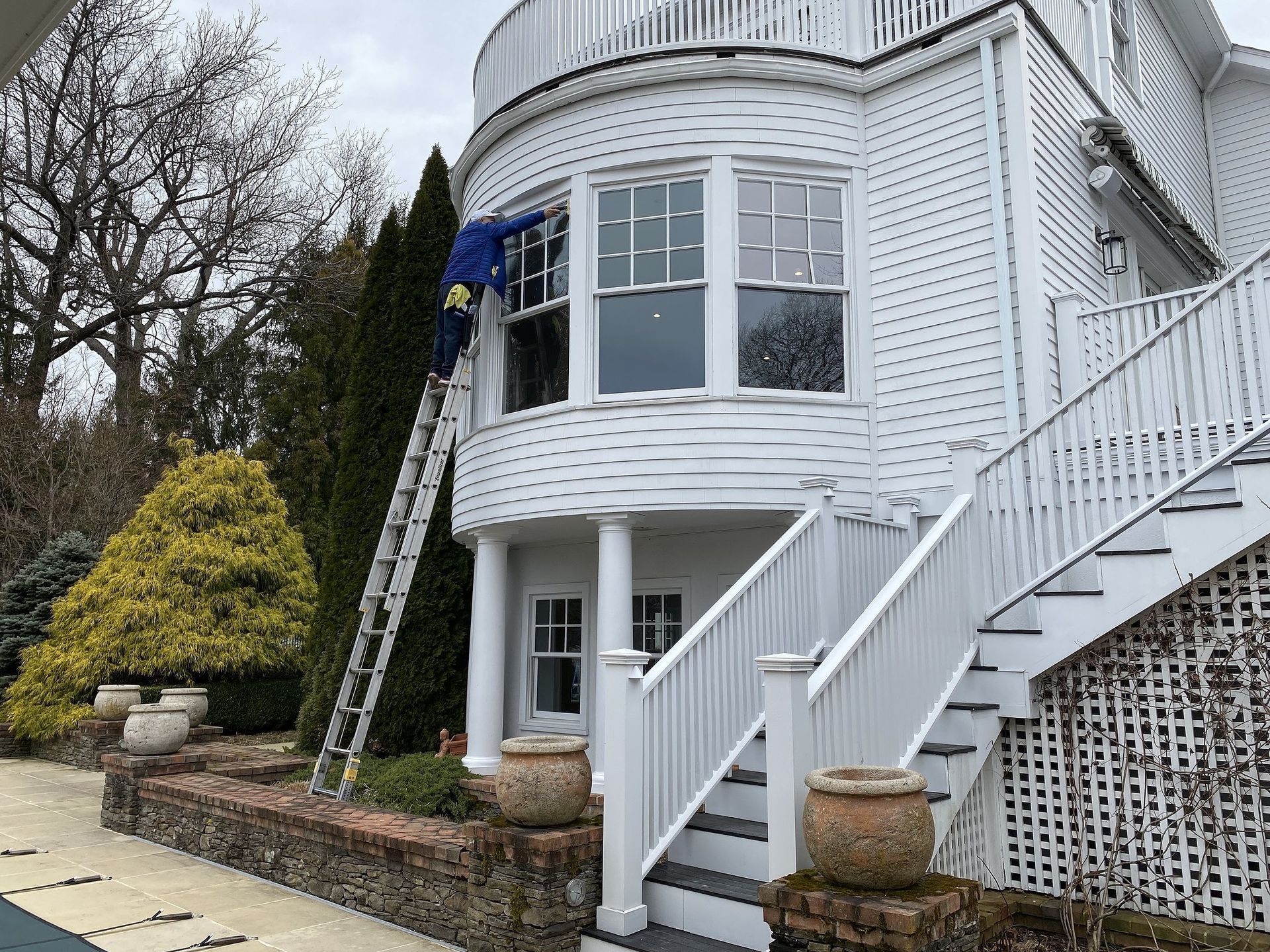 White house exterior with bay windows, staircase, and ladder leaning against the wall