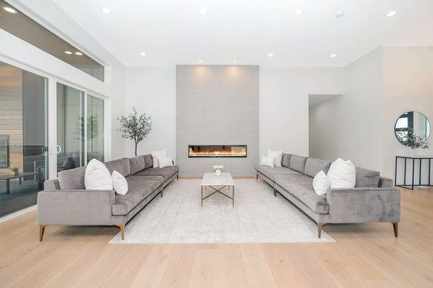 Bright modern living room with two gray sofas facing a fireplace and large sliding glass doors