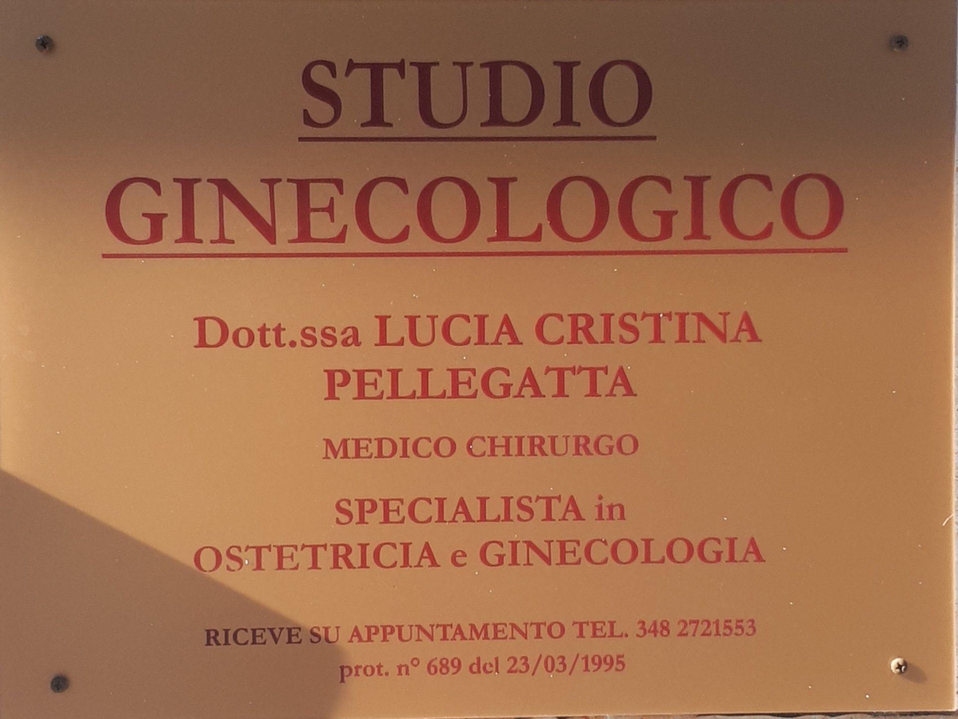 Insegna con la scritta «Studio Ginecologico», il nome del medico e le specializzazioni mediche in rosso su sfondo beige