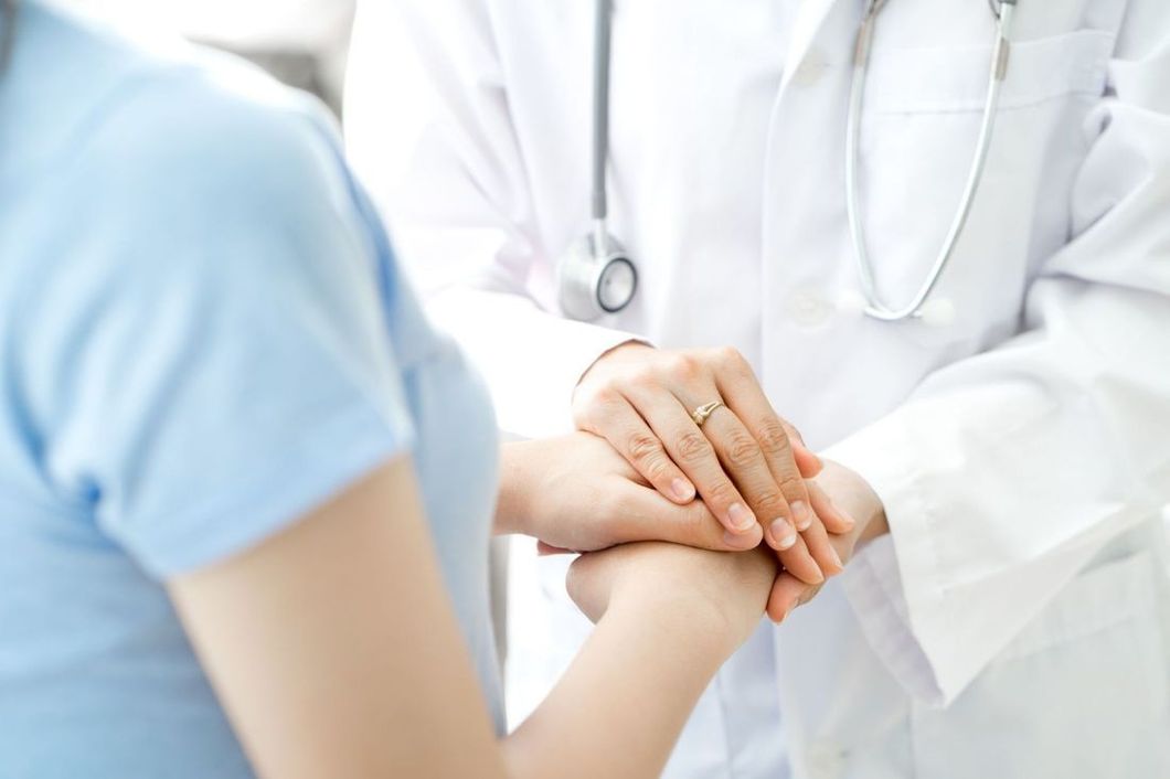 Un medico consola un paziente tenendogli la mano in una clinica luminosa