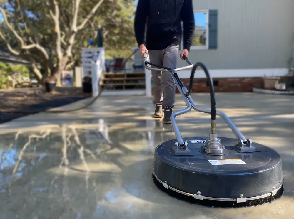 A man is cleaning a driveway with a machine.