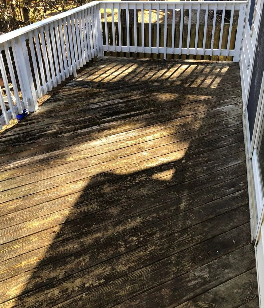 A wooden deck with a white railing and a shadow of a tree on it.