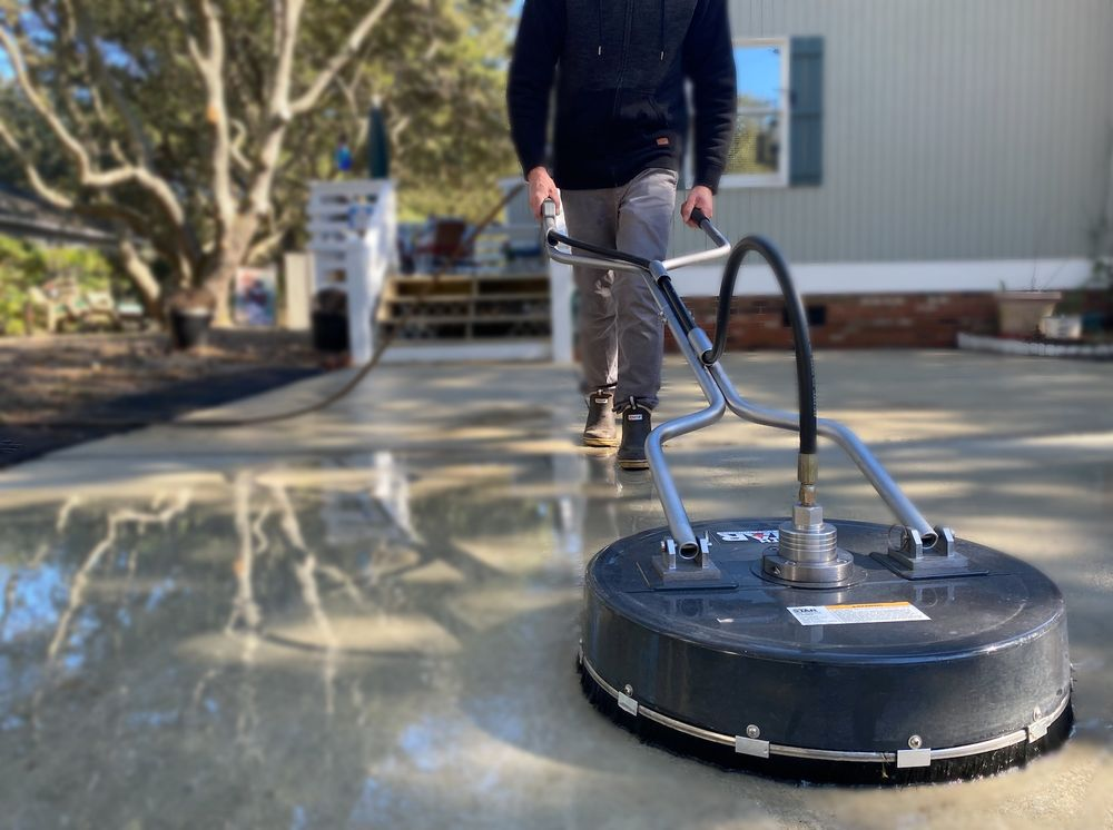 A man is cleaning a driveway with a machine.
