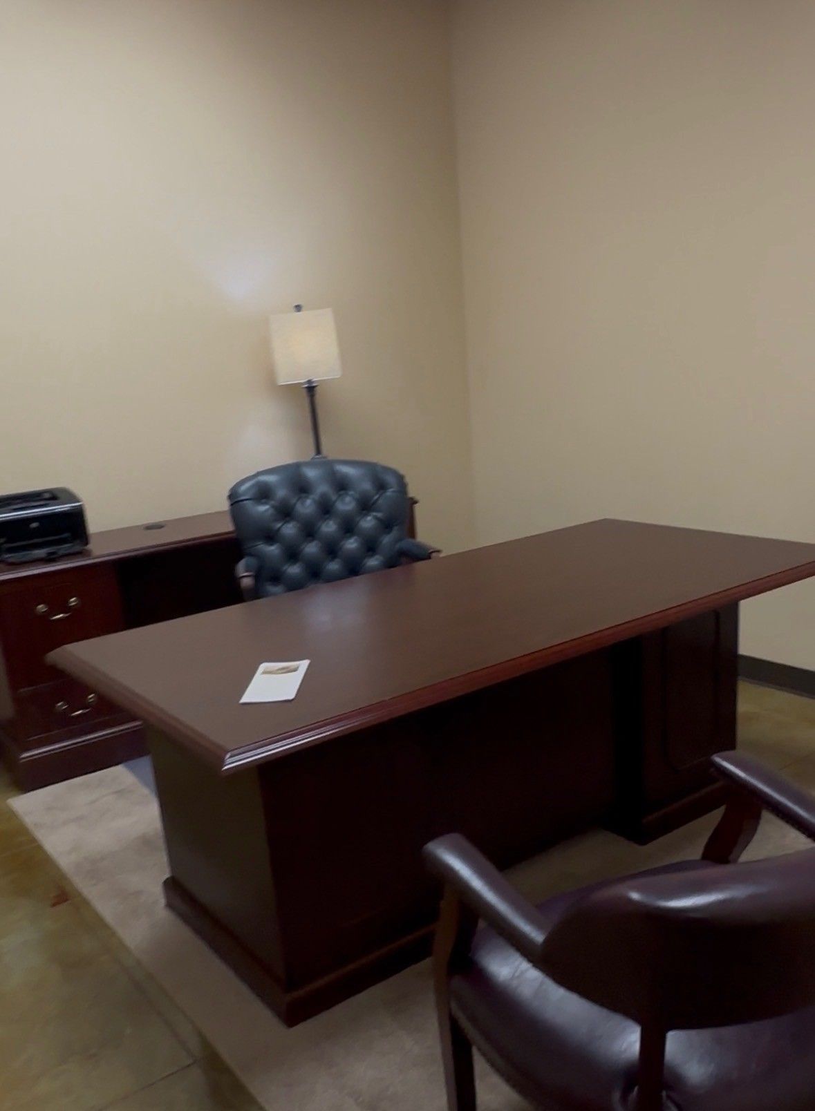 A waiting room with chairs, a fireplace console, and office partitions under recessed lighting.