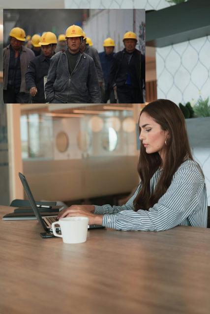 Woman working on laptop, with workers in background wearing hard hats.