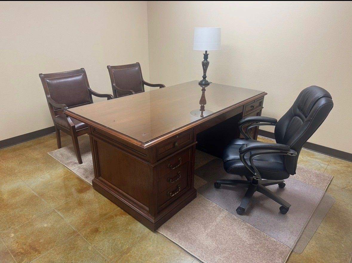 Dark wood office with desk, chairs, lamps, and beige walls.